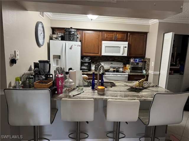 5307 Summerlin Rd Unit 704, Fort Myers, FL 33919 - kitchen featuring white appliances, ornamental molding, a kitchen bar, light stone counters, and backsplash