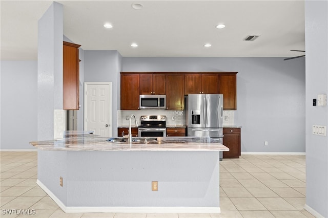 8169 Silver Birch Way, Lehigh Acres, FL 33971 - kitchen featuring appliances with stainless steel finishes, a peninsula, light tile patterned floors, decorative backsplash, and recessed lighting