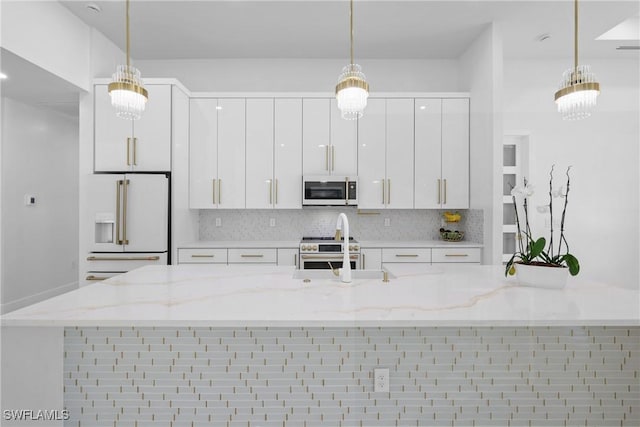 192 Herron Rd, North Fort Myers, FL 33903 - kitchen featuring premium appliances, white cabinetry, backsplash, decorative light fixtures, and modern cabinets