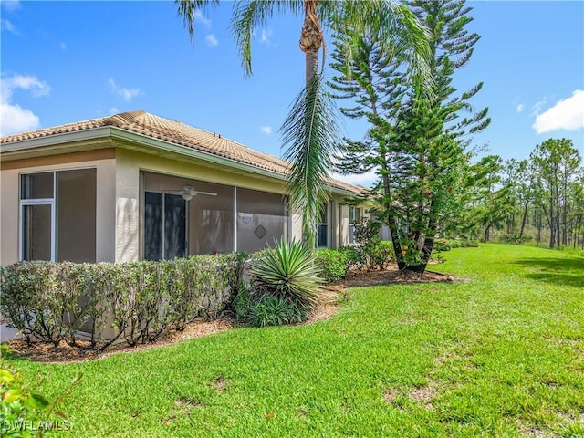 20698 Marathona Ct, North Fort Myers, FL 33917 - view of side of home featuring a yard, stucco siding, a tile roof, and a sunroom