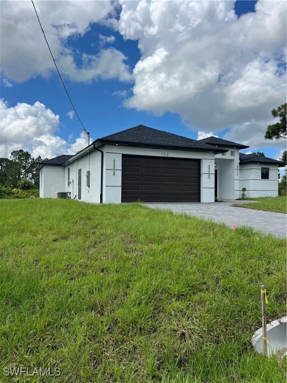 756 Chemstrand St E, Lehigh Acres, FL 33974 - view of front of property with a garage, stucco siding, a front yard, and driveway