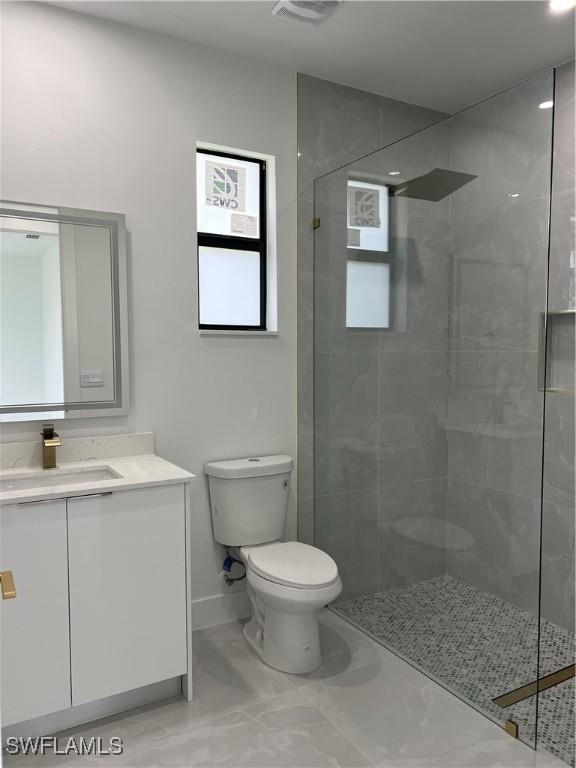 756 Chemstrand St E, Lehigh Acres, FL 33974 - bathroom with vanity, a tile shower, and marble finish flooring