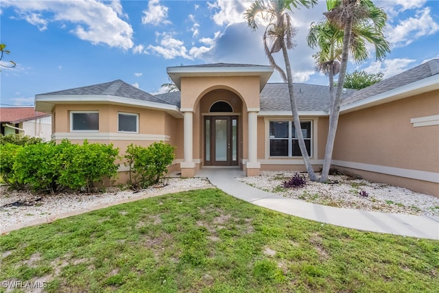 4200 SW 3rd Ave, Cape Coral, FL 33914 - view of exterior entry featuring stucco siding, a lawn, and roof with shingles