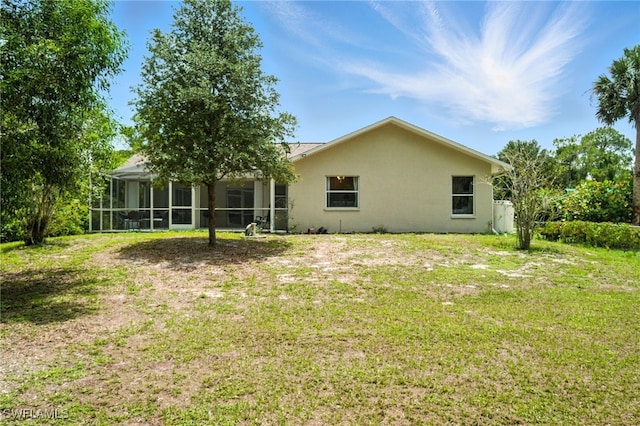 2711 4th St NW, Naples, FL 34120 - rear view of house with stucco siding, a yard, and a sunroom