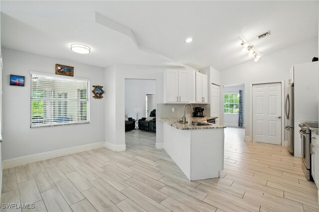 2711 4th St NW, Naples, FL 34120 - kitchen with stainless steel appliances, light stone countertops, a peninsula, white cabinetry, and decorative backsplash