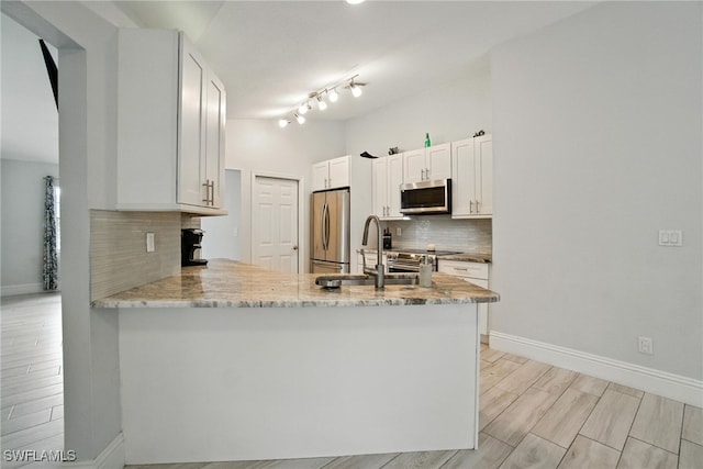 2711 4th St NW, Naples, FL 34120 - kitchen featuring appliances with stainless steel finishes, a peninsula, tasteful backsplash, light stone counters, and white cabinets