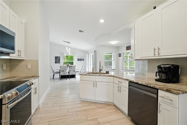 2711 4th St NW, Naples, FL 34120 - kitchen featuring stainless steel appliances, a peninsula, white cabinetry, vaulted ceiling, and light stone counters