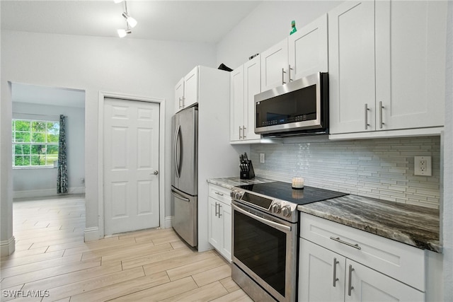 2711 4th St NW, Naples, FL 34120 - kitchen with appliances with stainless steel finishes, dark stone countertops, white cabinets, backsplash, and light wood-type flooring