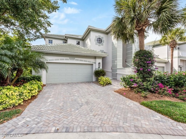 26690 Egrets Landing Dr Unit 101, Bonita Springs, FL 34134 - mediterranean / spanish-style house with decorative driveway, stucco siding, a garage, and a tile roof