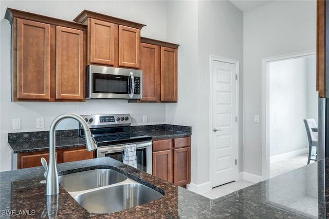 3457 NE 18th Pl, Cape Coral, FL 33909 - kitchen with stainless steel appliances, dark stone counters, brown cabinets, and tile patterned flooring
