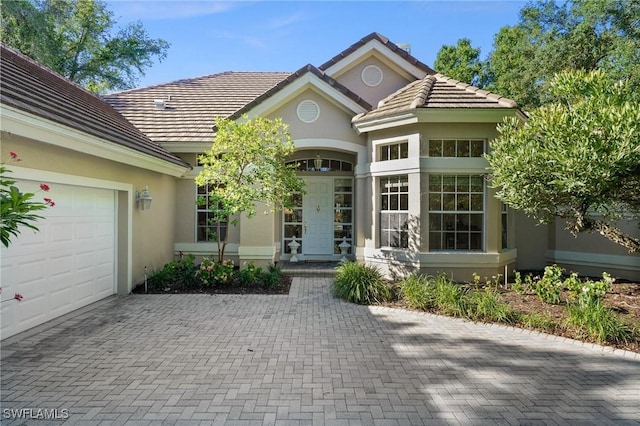 24881 Pennyroyal Dr, Bonita Springs, FL 34134 - entrance to property featuring stucco siding, decorative driveway, a garage, and a tiled roof