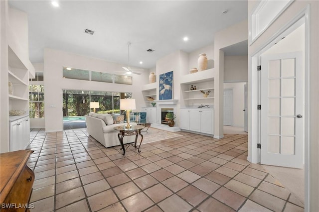 24881 Pennyroyal Dr, Bonita Springs, FL 34134 - living room with built in features, a ceiling fan, a fireplace with raised hearth, recessed lighting, and light tile patterned flooring