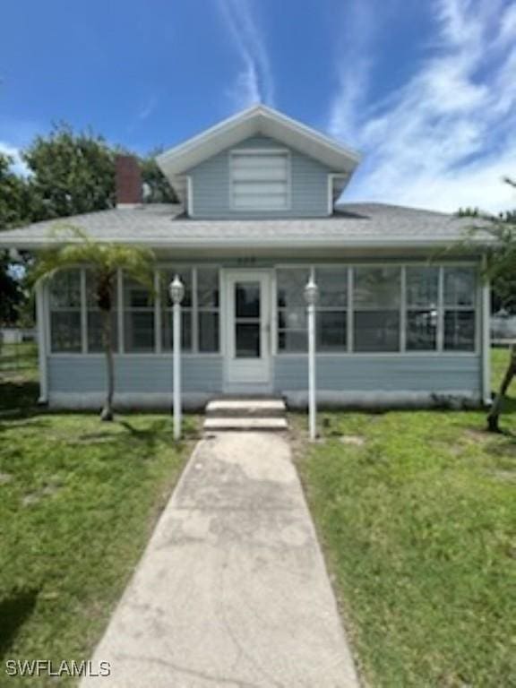 539 E Pasadena Ave, Clewiston, FL 33440 - bungalow-style house featuring a sunroom, a front lawn, and a chimney