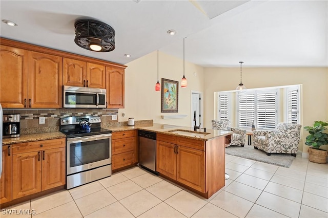 2548 River Reach Dr, Naples, FL 34104 - kitchen with stainless steel appliances, a peninsula, brown cabinets, light stone countertops, and decorative backsplash