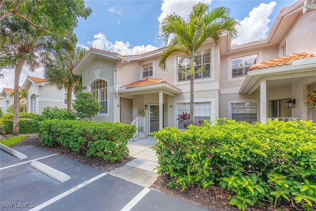 2450 Old Groves Rd Unit 201, Naples, FL 34109 - view of front of house with a tiled roof, stucco siding, and uncovered parking