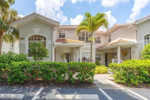 2450 Old Groves Rd Unit 201, Naples, FL 34109 - view of front facade featuring uncovered parking, a tile roof, and stucco siding