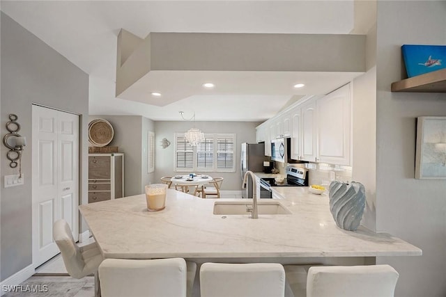 2450 Old Groves Rd Unit 201, Naples, FL 34109 - kitchen with stainless steel appliances, a peninsula, white cabinets, a breakfast bar, and recessed lighting
