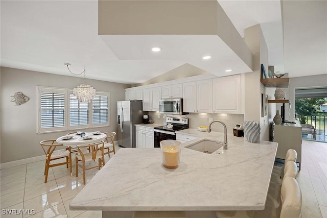2450 Old Groves Rd Unit 201, Naples, FL 34109 - kitchen featuring stainless steel appliances, light stone countertops, a peninsula, a chandelier, and recessed lighting