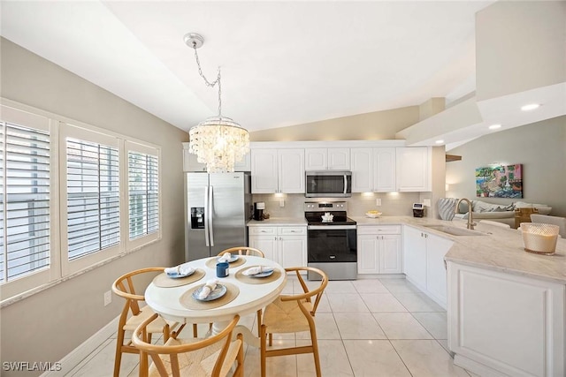 2450 Old Groves Rd Unit 201, Naples, FL 34109 - kitchen with stainless steel appliances, a peninsula, a chandelier, decorative backsplash, and white cabinetry