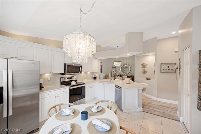 2450 Old Groves Rd Unit 201, Naples, FL 34109 - kitchen featuring stainless steel appliances, a peninsula, a chandelier, light countertops, and recessed lighting