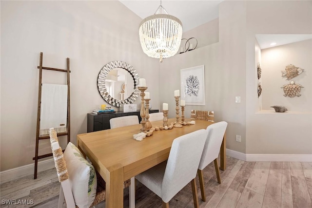 2450 Old Groves Rd Unit 201, Naples, FL 34109 - dining room featuring a chandelier, wood finished floors, and a high ceiling