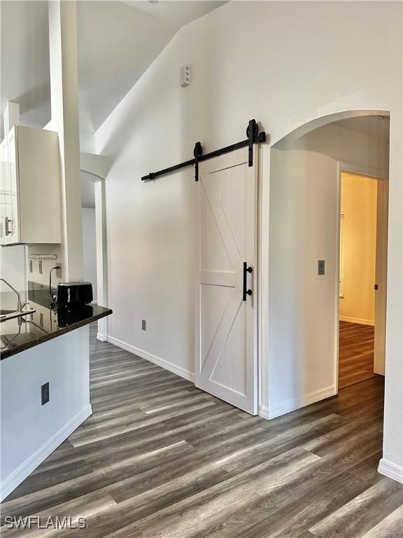 2675 70th Ave NE, Naples, FL 34120 - kitchen featuring dark wood-style floors, dark countertops, arched walkways, lofted ceiling, and a barn door