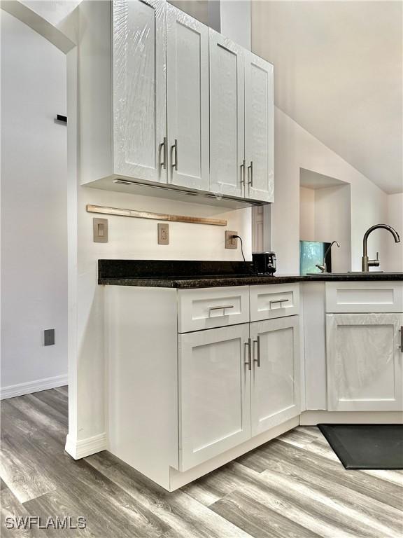 2675 70th Ave NE, Naples, FL 34120 - kitchen featuring light wood finished floors, white cabinets, dark stone counters, and lofted ceiling