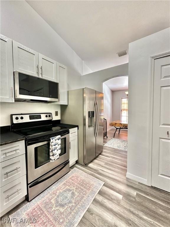 2675 70th Ave NE, Naples, FL 34120 - kitchen with appliances with stainless steel finishes, arched walkways, vaulted ceiling, light wood-style flooring, and dark countertops