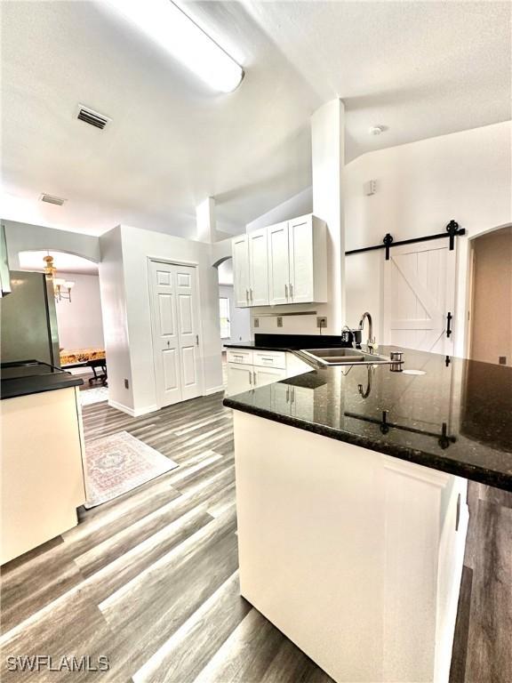2675 70th Ave NE, Naples, FL 34120 - kitchen featuring arched walkways, white cabinets, wood finished floors, and freestanding refrigerator