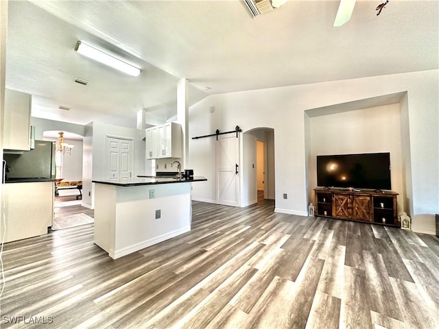 2675 70th Ave NE, Naples, FL 34120 - kitchen with a barn door, dark countertops, arched walkways, white cabinetry, and wood finished floors