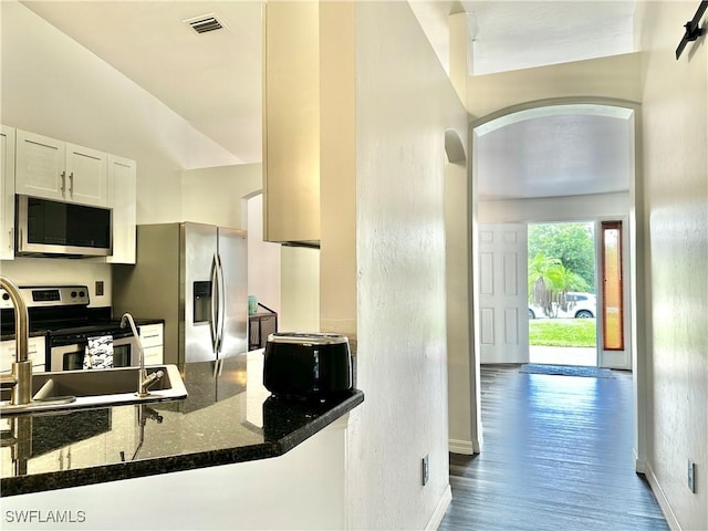 2675 70th Ave NE, Naples, FL 34120 - kitchen with appliances with stainless steel finishes, arched walkways, dark stone countertops, white cabinetry, and wood finished floors