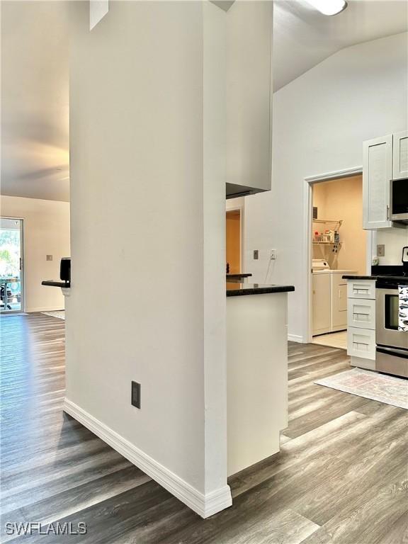 2675 70th Ave NE, Naples, FL 34120 - kitchen with appliances with stainless steel finishes, wood finished floors, separate washer and dryer, dark countertops, and lofted ceiling