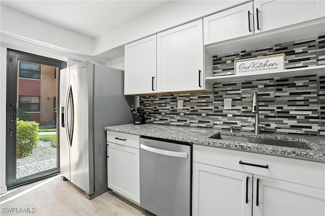 1506 Mainsail Dr Unit 1, Naples, FL 34114 - kitchen featuring appliances with stainless steel finishes, white cabinetry, tasteful backsplash, light stone counters, and light wood-type flooring