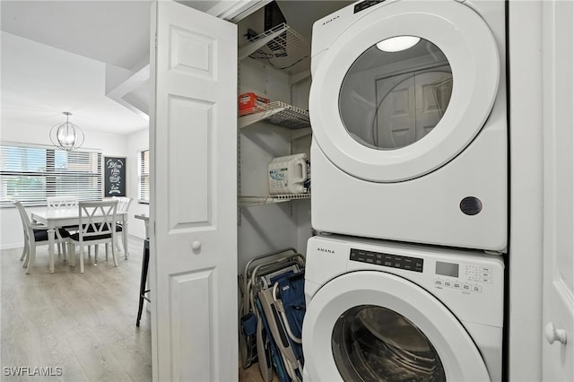 1506 Mainsail Dr Unit 1, Naples, FL 34114 - laundry area featuring stacked washing machine and dryer, wood finished floors, and a chandelier