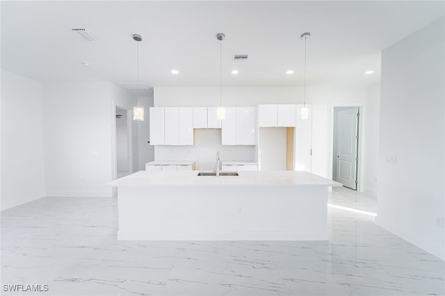 1268 Hillcrest St E, Lehigh Acres, FL 33974 - kitchen featuring white cabinetry, recessed lighting, an island with sink, light marble finish floors, and light countertops