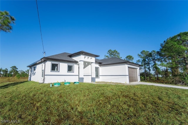 1268 Hillcrest St E, Lehigh Acres, FL 33974 - prairie-style house featuring a front yard, stucco siding, a garage, driveway, and roof with shingles