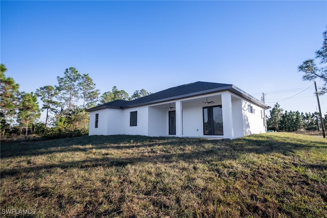 1268 Hillcrest St E, Lehigh Acres, FL 33974 - rear view of house with a ceiling fan, stucco siding, and a lawn