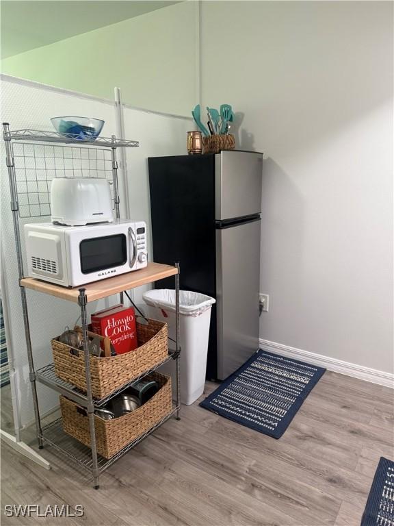 240 N Collier Blvd Unit A3, Marco Island, FL 34145 - kitchen with freestanding refrigerator, white microwave, and wood finished floors