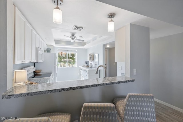 18068 San Carlos Blvd Unit 515, Fort Myers Beach, FL 33931 - kitchen with white appliances, wood finished floors, ceiling fan, a raised ceiling, and a peninsula