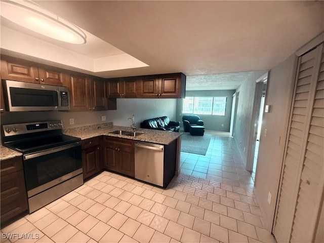 606 Gerald Ave Unit 115, Lehigh Acres, FL 33936 - kitchen with appliances with stainless steel finishes, light tile patterned floors, light stone countertops, and dark brown cabinets