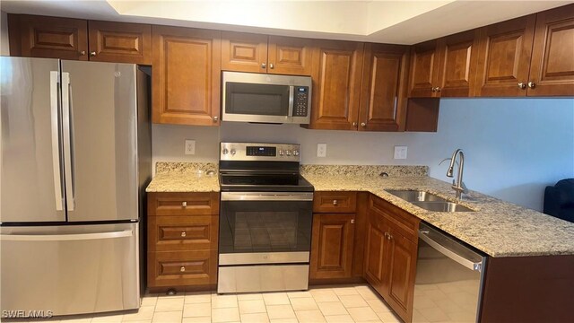 606 Gerald Ave Unit 115, Lehigh Acres, FL 33936 - kitchen with appliances with stainless steel finishes, light stone countertops, light tile patterned floors, and brown cabinetry