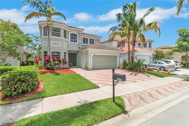 8677 Pegasus Dr, Lehigh Acres, FL 33971 - mediterranean / spanish house featuring decorative driveway, an attached garage, a tiled roof, stucco siding, and a front lawn