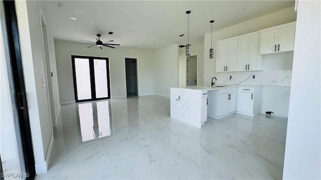 2503 46th St SW, Lehigh Acres, FL 33976 - kitchen with white cabinets, tasteful backsplash, light marble finish flooring, a ceiling fan, and decorative light fixtures
