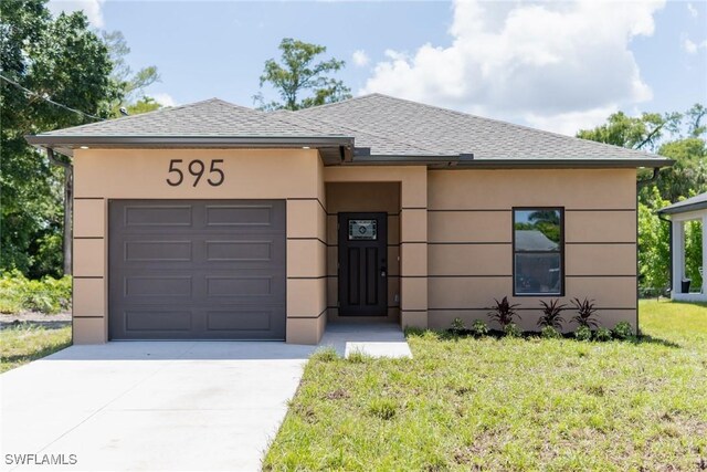 595 Carolina Ave, Fort Myers, FL 33905 - view of front facade featuring an attached garage, driveway, a front yard, stucco siding, and roof with shingles