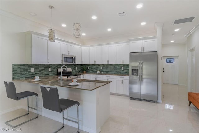 595 Carolina Ave, Fort Myers, FL 33905 - kitchen featuring stainless steel appliances, a peninsula, decorative backsplash, white cabinetry, and crown molding