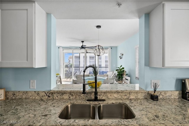 4411 Bay Beach Ln Unit 744, Fort Myers Beach, FL 33931 - kitchen featuring light stone counters, ceiling fan, white cabinets, and pendant lighting