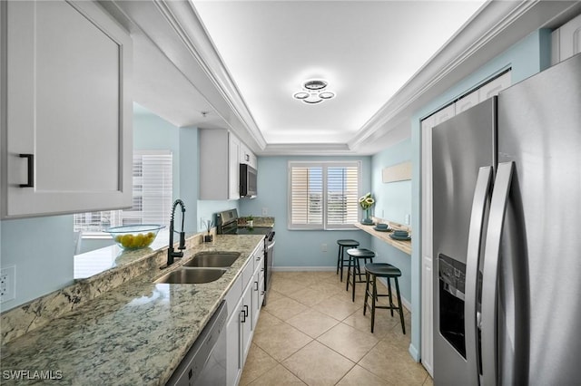 4411 Bay Beach Ln Unit 744, Fort Myers Beach, FL 33931 - kitchen with appliances with stainless steel finishes, a tray ceiling, light stone counters, white cabinetry, and light tile patterned flooring