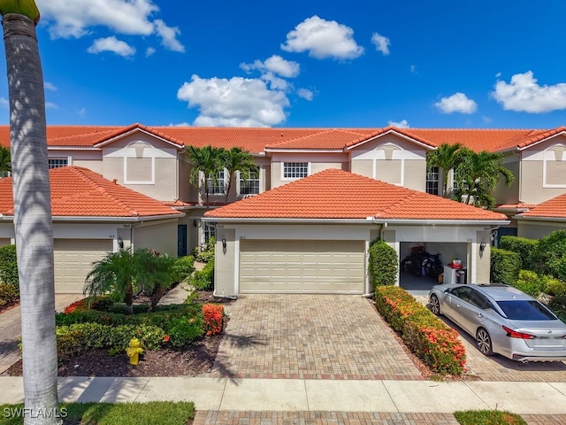 9260 Belleza Way Unit 203, Fort Myers, FL 33908 - view of front facade with a tile roof, an attached garage, decorative driveway, and stucco siding