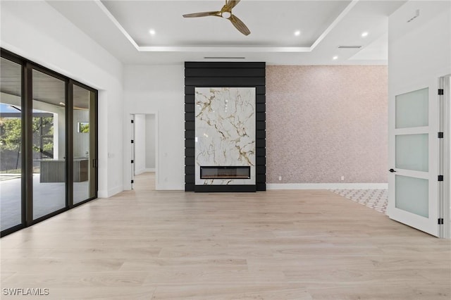 3620 SW 4th Ln, Cape Coral, FL 33991 - unfurnished living room featuring a tray ceiling, wood finished floors, a premium fireplace, ceiling fan, and recessed lighting