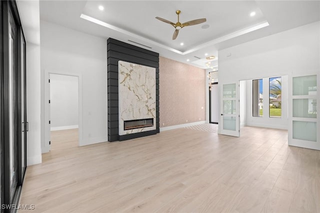 3620 SW 4th Ln, Cape Coral, FL 33991 - unfurnished living room with a tray ceiling, a ceiling fan, a fireplace, light wood-type flooring, and recessed lighting